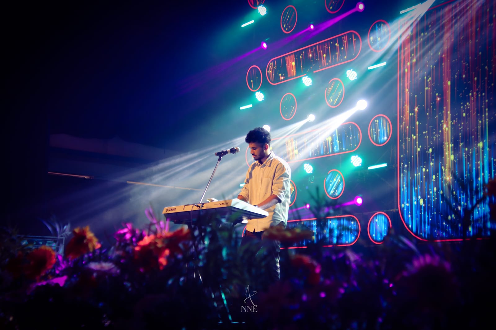 A keyboard player mid-song under stage lights
