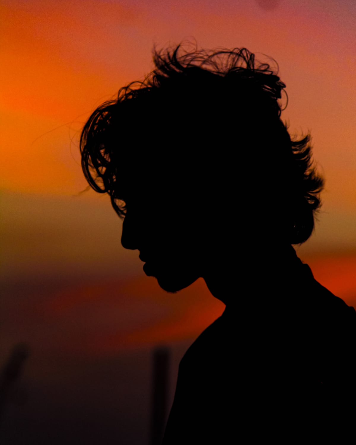 A profile in silhouette against an orange sunset