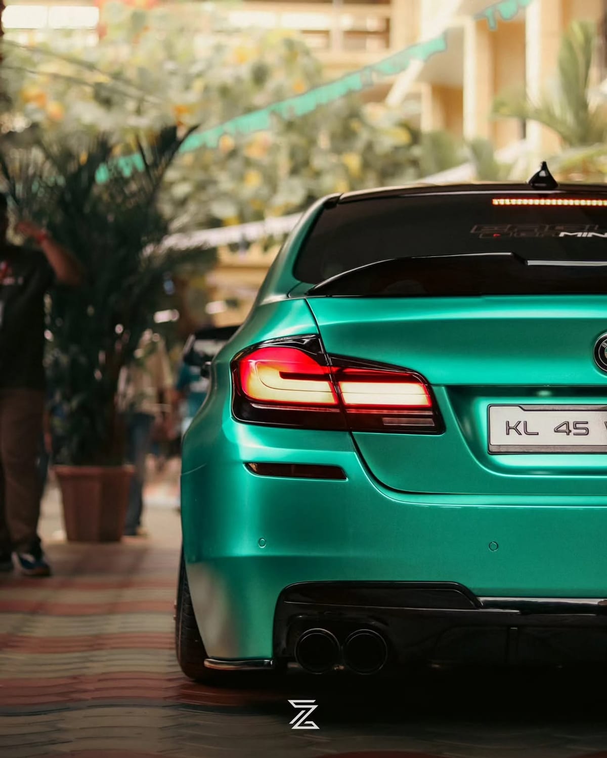 The rear of a turquoise BMW parked under bunting