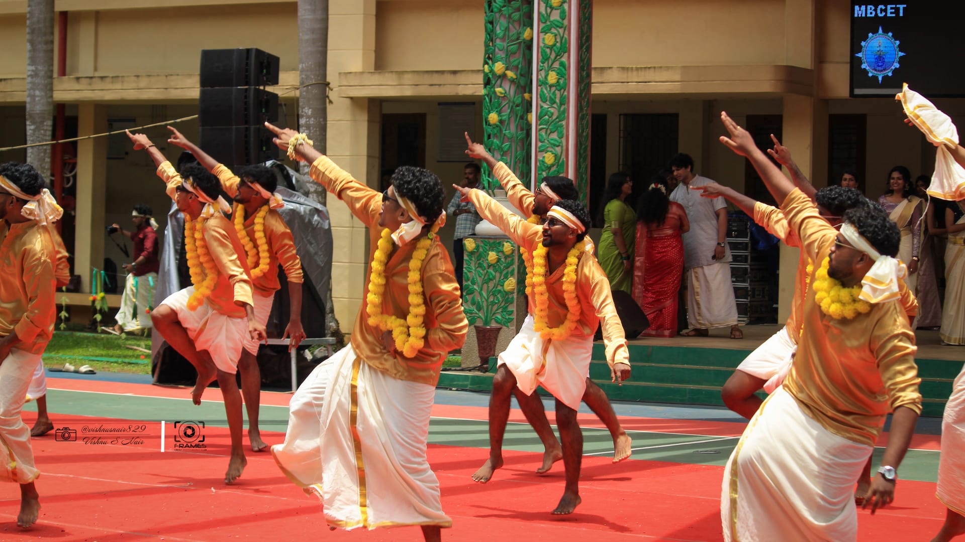 Dancers in gold and white mid-step during the Onam celebration